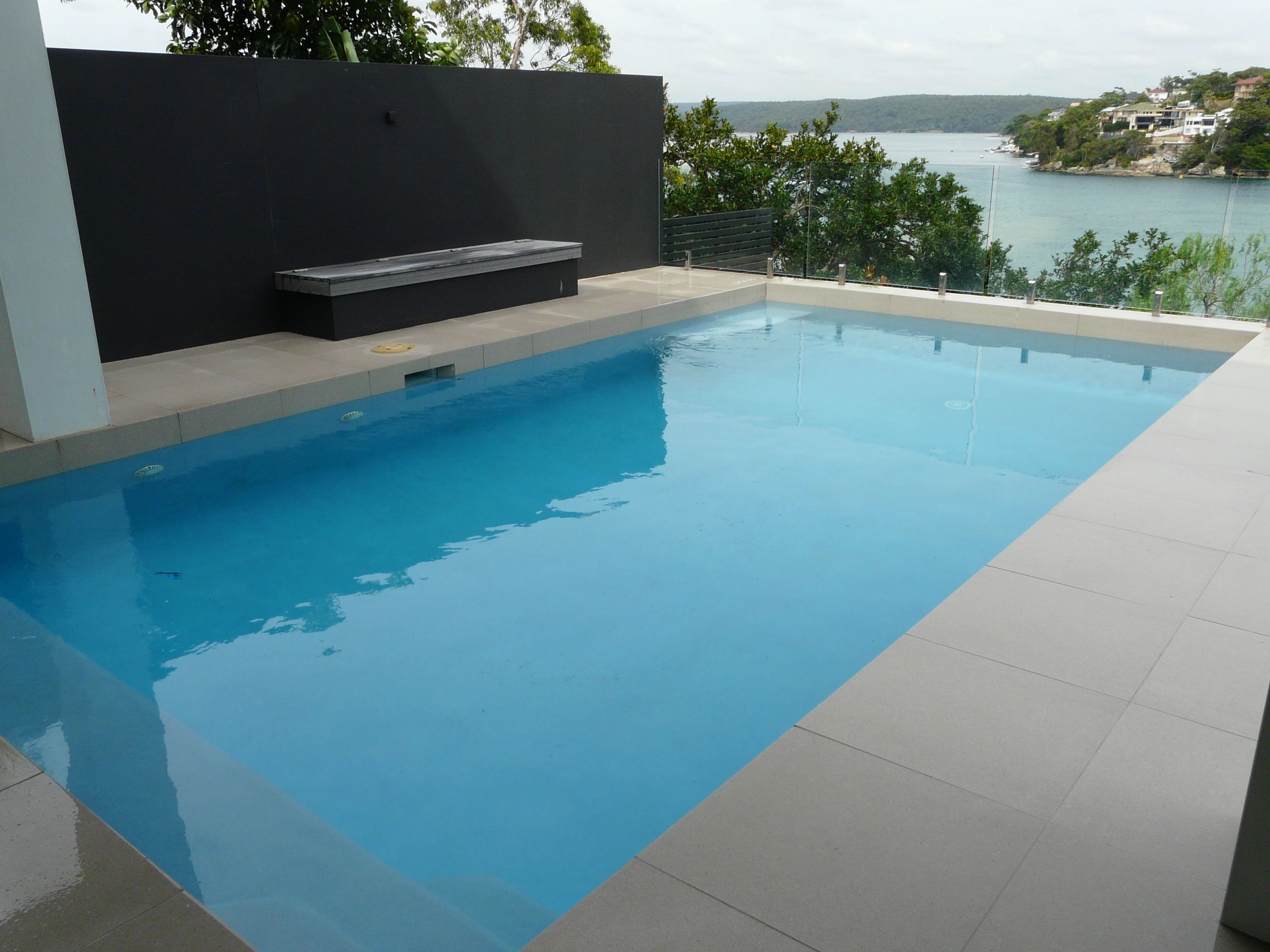 Modern backyard pool with scenic water view and minimalist design.