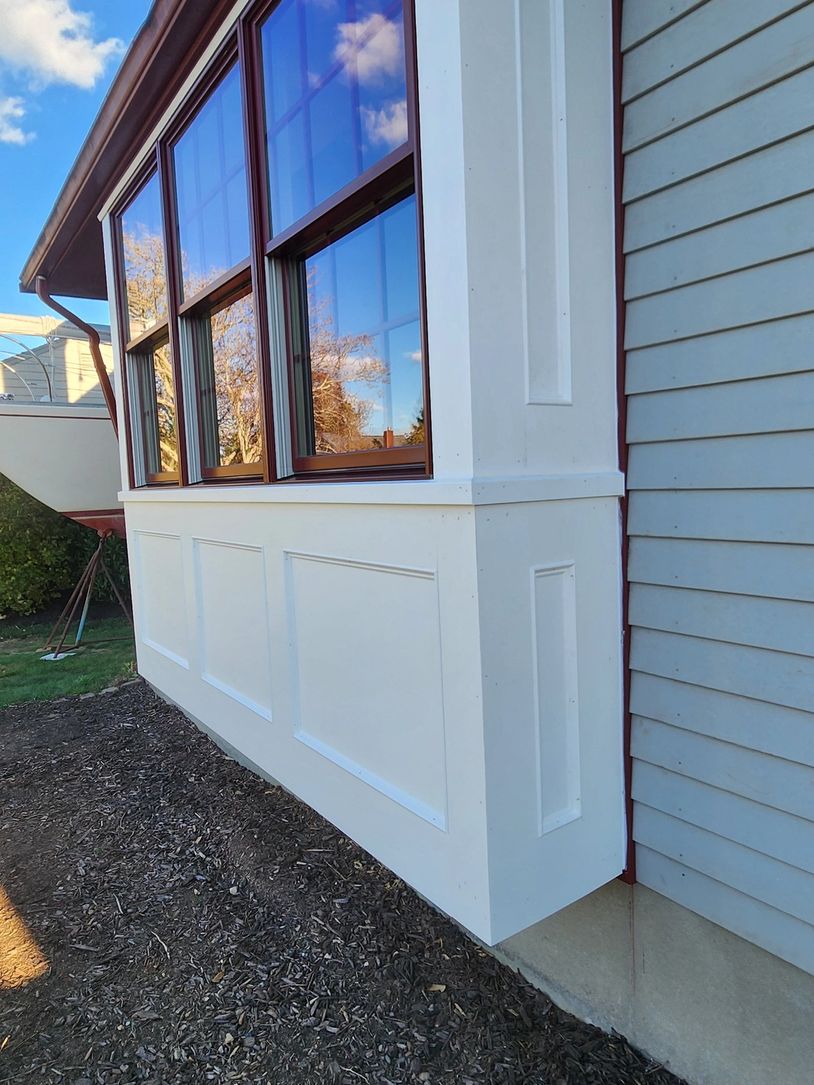 White bay window with reflective glass on a house exterior.