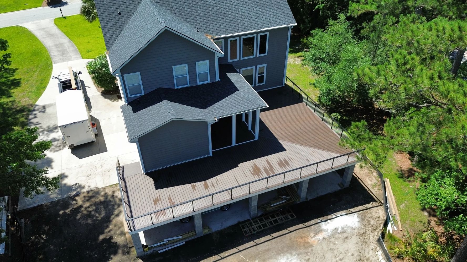 A two-story house with a large wooden deck under construction.