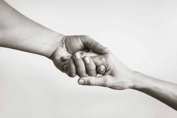 Two hands gently holding each other symbolizing support and care.