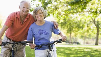 senior man and woman smiling on bikes