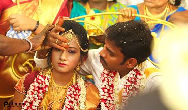 Traditional Indian wedding ceremony with bride and groom adorned in gold and flower garlands.