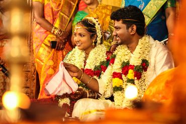 Traditional Indian wedding couple adorned with floral garlands and vibrant attire.