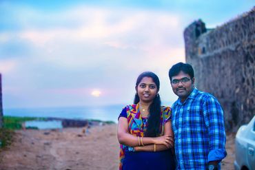 Couple standing together by historic fort at sunset in Thanjavur by Luster Pearl Media.