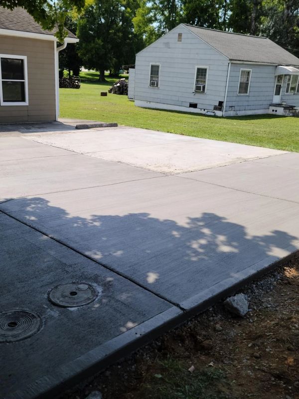A newly paved concrete driveway beside a house with green lawn.