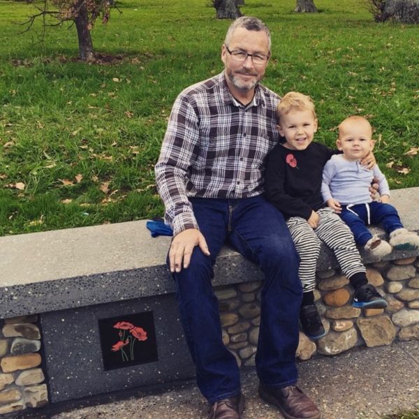 Man with two young children sitting on a stone bench.
