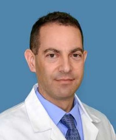 Portrait of a male doctor in white coat against blue background.
