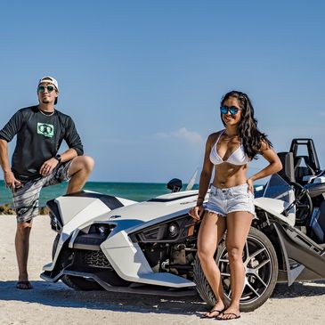 Boyfriend and girlfriend smiling while hanging out by a slingshot that they are using on the beach