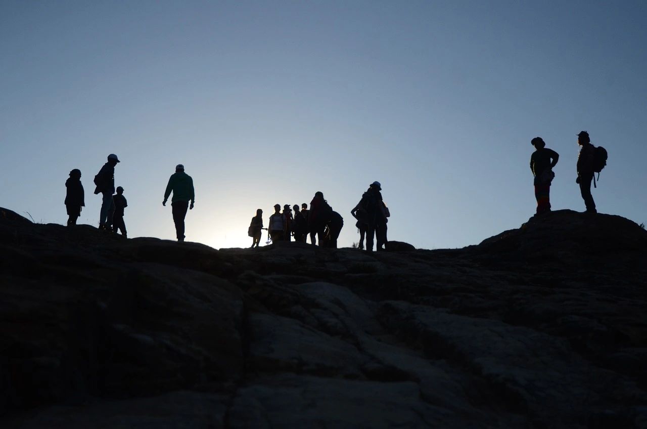 Silhouettes of people hiking at sunset.