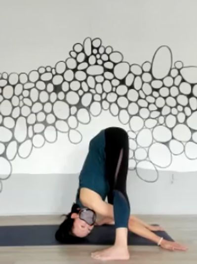 Yoga teacher Kaori in a standing forward fold yoga pose.