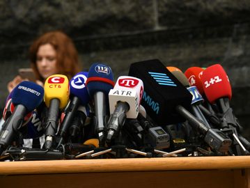 A cluster of microphones from various news outlets ready for a press conference.