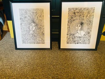 Two framed intricate black-and-white drawings featuring female faces and detailed patterns.