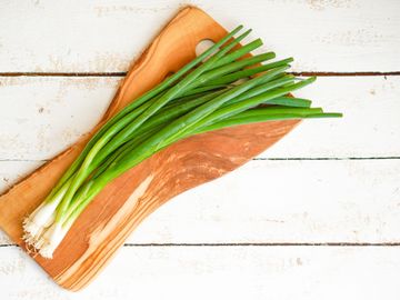 Scallions on a wooden chopping board