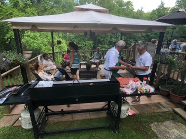 People enjoying a barbecue under a gazebo in a garden.