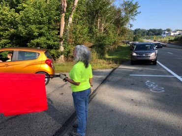 Person holding a red flag near cars on a road.
