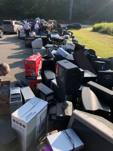 Pile of old electronics and appliances outdoors.