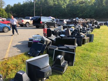 A long row of old computer monitors and electronics outside.