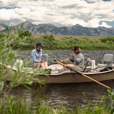 man and woman in a drift boat surrounded by mountains