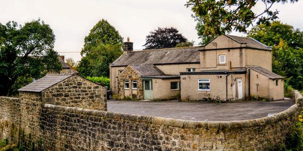 Stone house with a large courtyard enclosed by a stone wall.