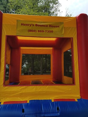 Colorful inflatable bounce house with a sign for Henry's Bounce House and contact number.