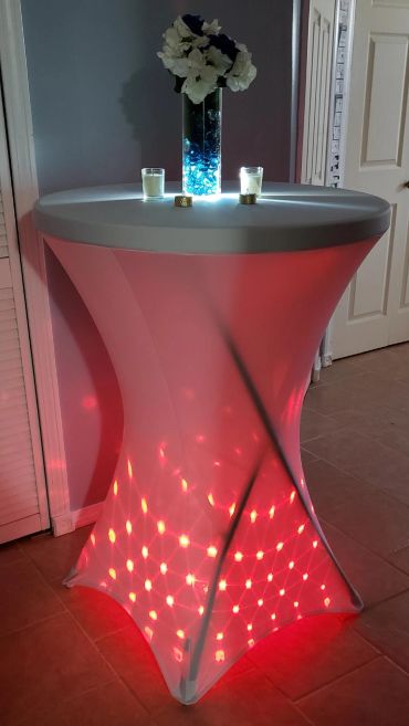 Illuminated cocktail table with flower vase and candles.