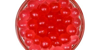 A bowl of red, translucent, spherical popping bobba.


