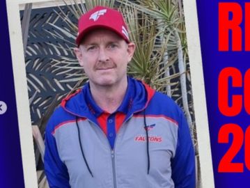 Man wearing a Falcons sports jacket and red cap posing outdoors.