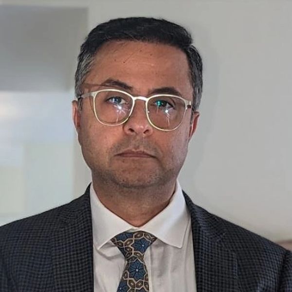 Man in suit and glasses looking at the camera.