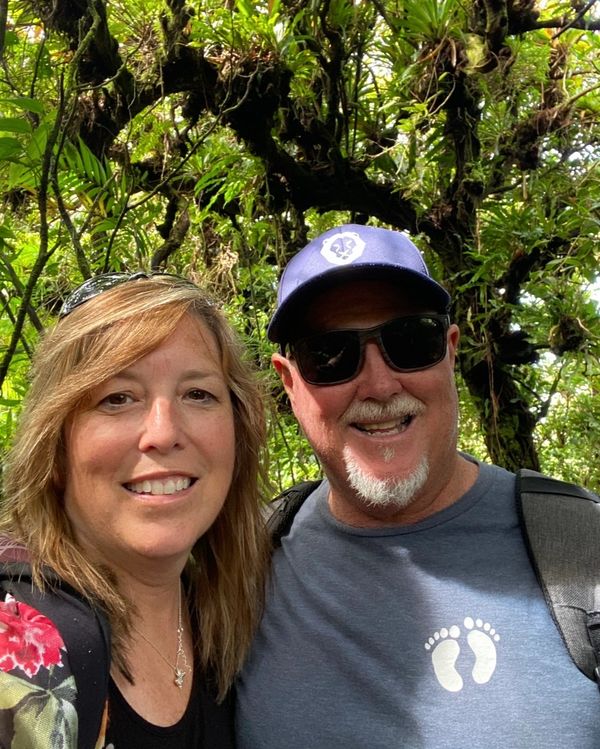 Smiling couple enjoys a nature hike surrounded by lush greenery.