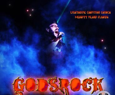 Man passionately singing on stage with dramatic blue lighting at Godstock event.