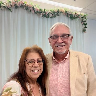 Smiling older couple posing together indoors with floral decorations.