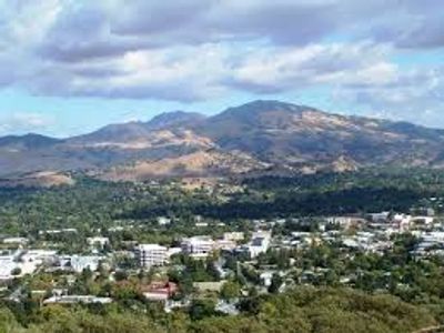 A cityscape with mountains in the background under a cloudy sky.