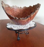 Decorative wooden bowl with natural edges on a metal stand.