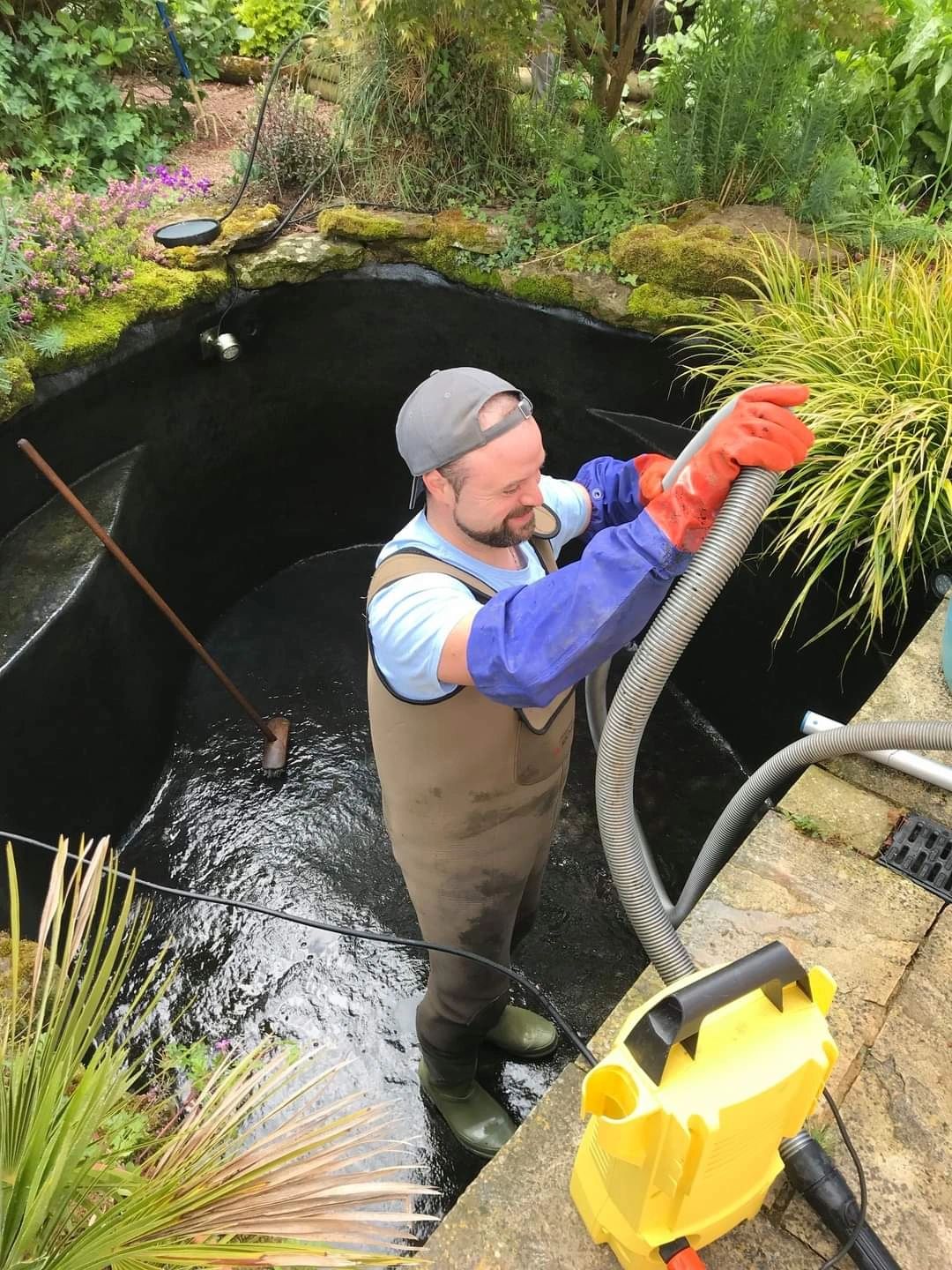 Professional UK pond specialist cleaning a domestic garden pond