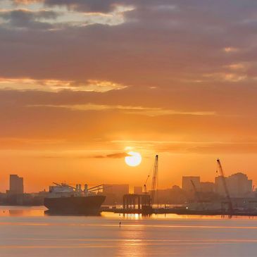 Sun rising over an industrial harbor scene