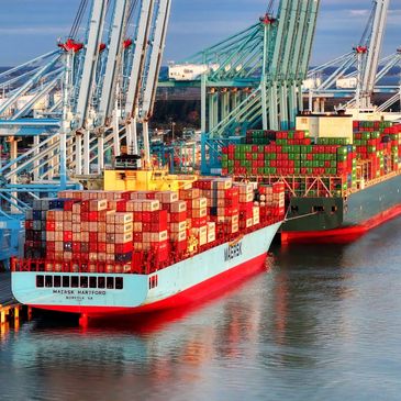 Two container ships at a container terminal in front of cranes
