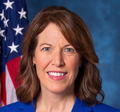 Professional woman in blue suit with American flag.