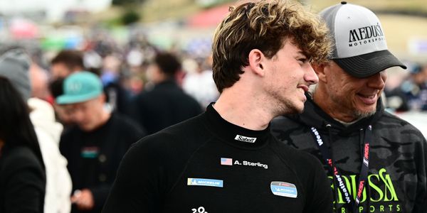 Two men smiling and talking at a crowded event.