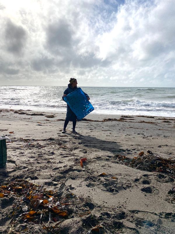 charlotte eatock holding a big sheet of blue plastic washed up on the coast