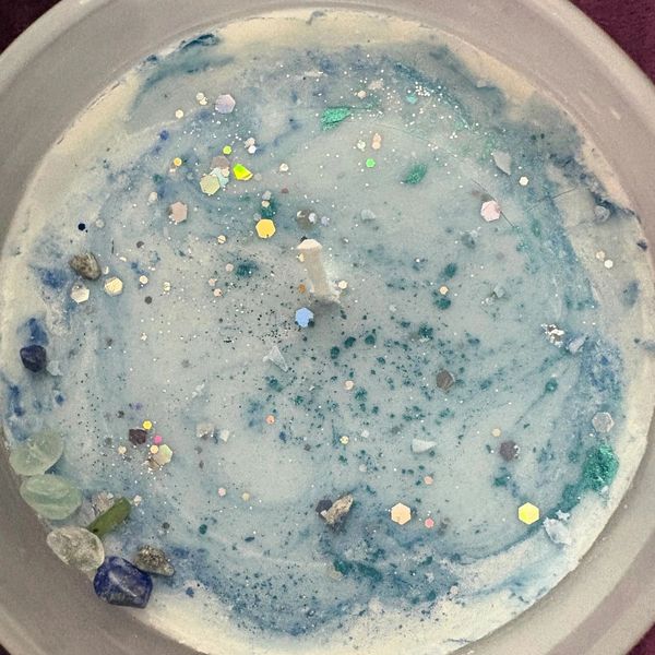 Close-up of a decorative candle with blue swirls and glitter.