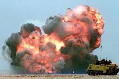 A large explosion occurs near a military vehicle in a desert area.