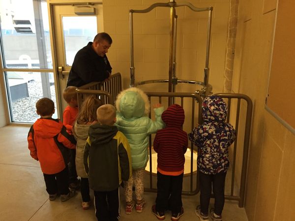 Children observing an adult near a water tank exhibit indoors.