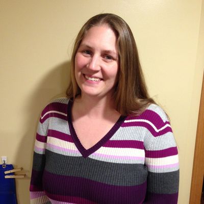 Smiling woman in a striped sweater standing indoors.
