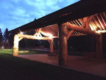 Wooden pavilion illuminated at dusk in a park.