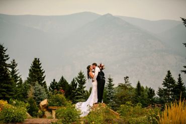Bride and groom kissing in a mountainous garden.