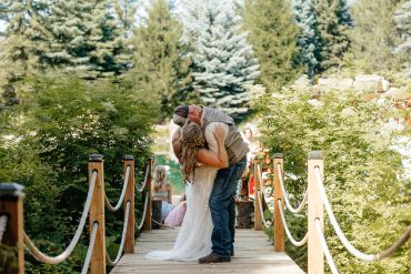 Couple kissing on a wooden bridge during wedding.