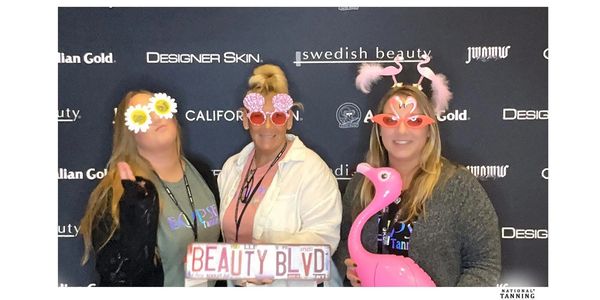 Three women at a beauty event with fun glasses and props.