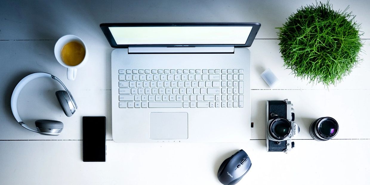 digital workspace with laptop, headphones, smartphone, camera, and lenses symbolizing web designing
