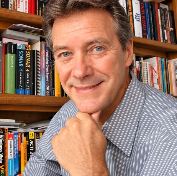 Smiling man posing in front of a bookshelf.