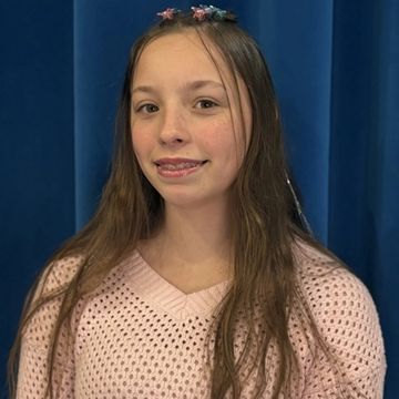 A smiling girl with braces wearing a pink sweater against a blue background.